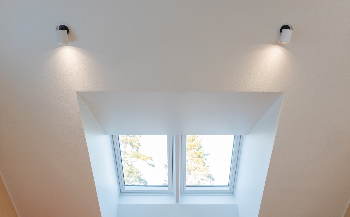 Valkoisessa katossa on kaksi LED-upotettua valaisinta, jotka valaisevat kirkkaasti kattolyhdyn. Kattolyhty päästä kahdesta suorakulmaisesta ikkunasta, ulos avautuvat näkymät siniselle taivaalle ja puiden latvoille. Tämä upea valaistuskokonaisuus on saatavilla LedStore.fi:stä, jossa laaja valikoima laadukkaita LED-valaisimia odottaa sinua luomaan täydellisen tunnelman kotiisi.